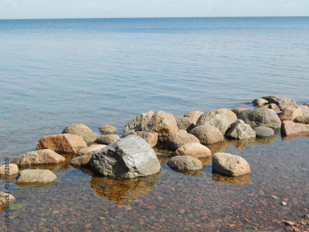 Seascape on a summer sunny day: stones near the shore, water Seascape on a summer sunny day: stones near the shore, water