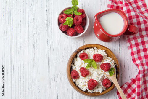 Cottage cheese with raspberries and green mint leaves, fresh berries and milk jug, healthy breakfast concept, top view
