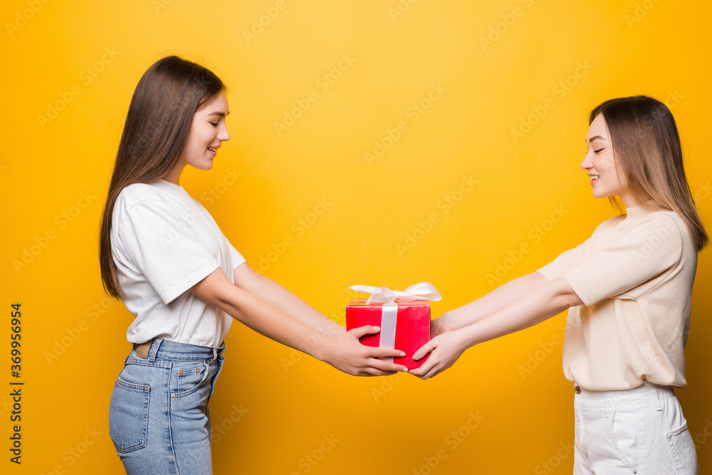 Side view of surprised young women hold present box with gift ribbon bow isolated on yellow background Women's Day birthday, holiday concept. Side view of surprised young women hold present box with gift ribbon bow isolated on yellow background Women's Day birthday, holiday concept.