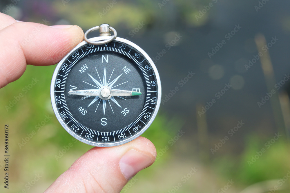 Old classic navigation compass in hand on natural background as symbol of tourism with compass, travel with compass and outdoor activities with compass Old classic navigation compass in hand on natural background as symbol of tourism with compass, travel with compass and outdoor activities with compass
