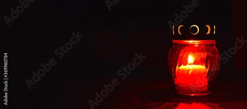 All Saints Day candle. Red votive candle on dark background photo