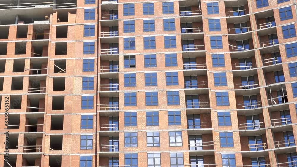 Facade of a high-rise residential building under construction. Brickwork walls and windows Facade of a high-rise residential building under construction. Brickwork walls and windows