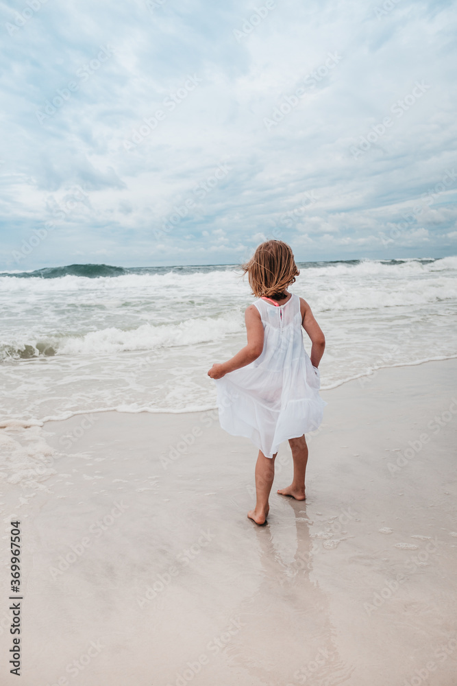 girl on beach facing the ocean and waves girl on beach facing the ocean and waves
