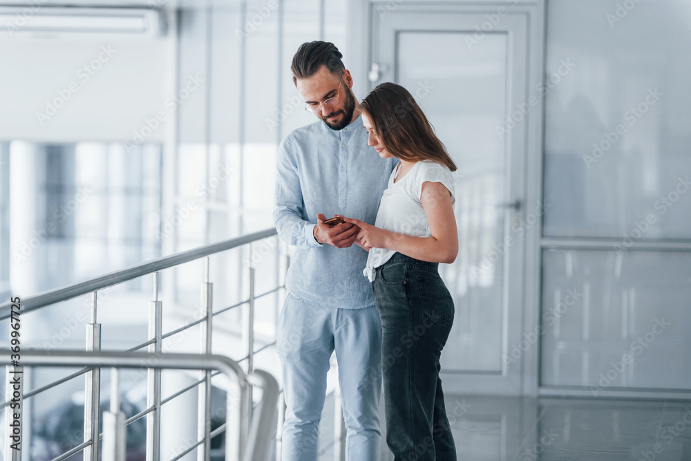 Young handsome man in formal clothes talking with girl indoors in the office at daytime Young handsome man in formal clothes talking with girl indoors in the office at daytime