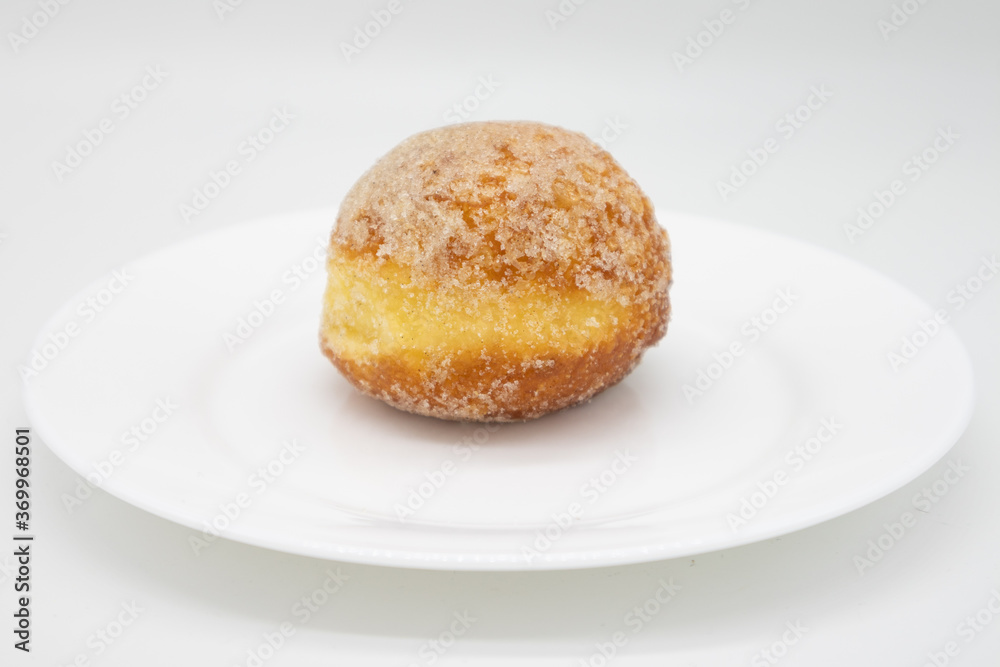 Simple Sugared Stuffed Custard Donut on a White Plate with a White Background Simple Sugared Stuffed Custard Donut on a White Plate with a White Background