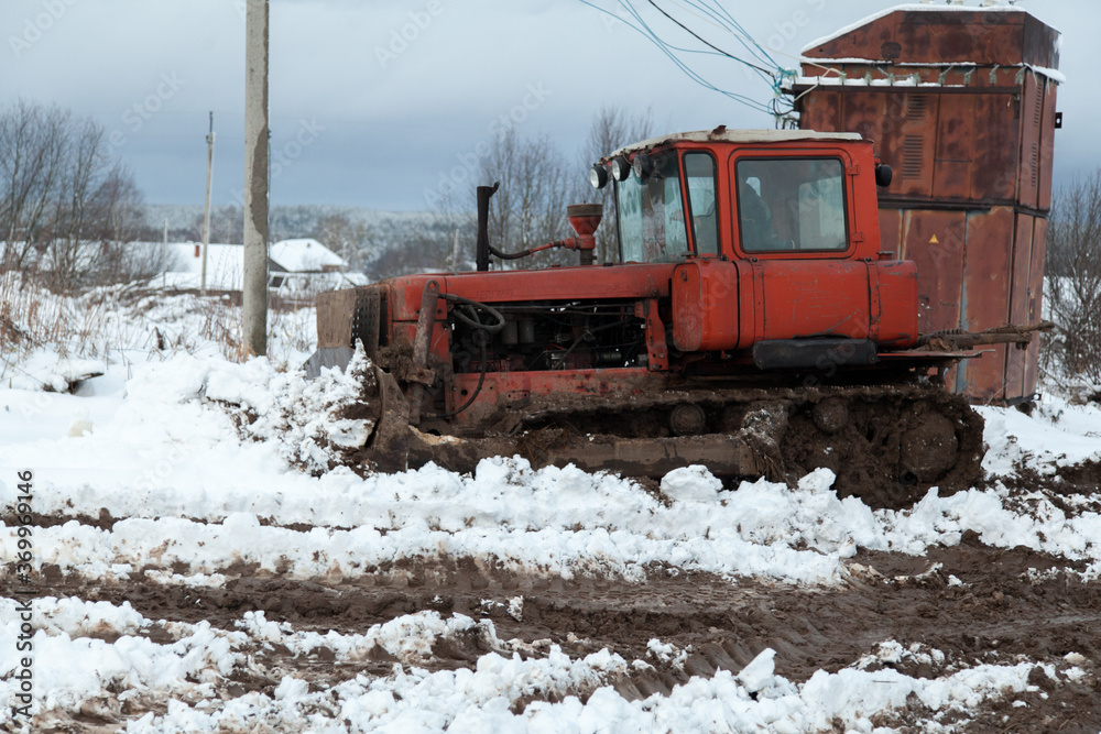 Old soviet tractor in snowy dirt road Old soviet tractor in snowy dirt road