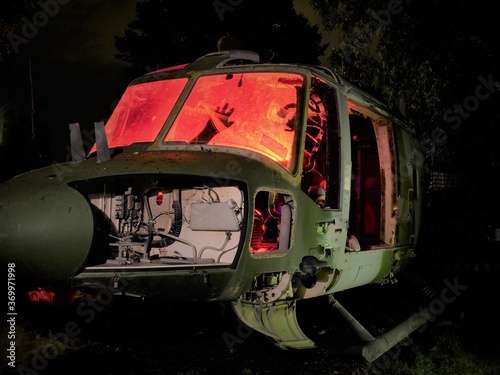 disused abandoned Helicopter grounded at night with red internal lighting to show hand silhouette, nose body and component parts 