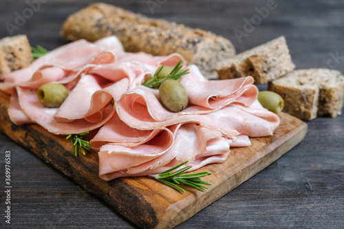 Traditional Italian antipasti mortadella on a wooden plate, served with olives