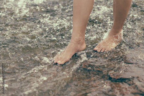 Woman legs relaxing with water on stone in the river for relax feeling