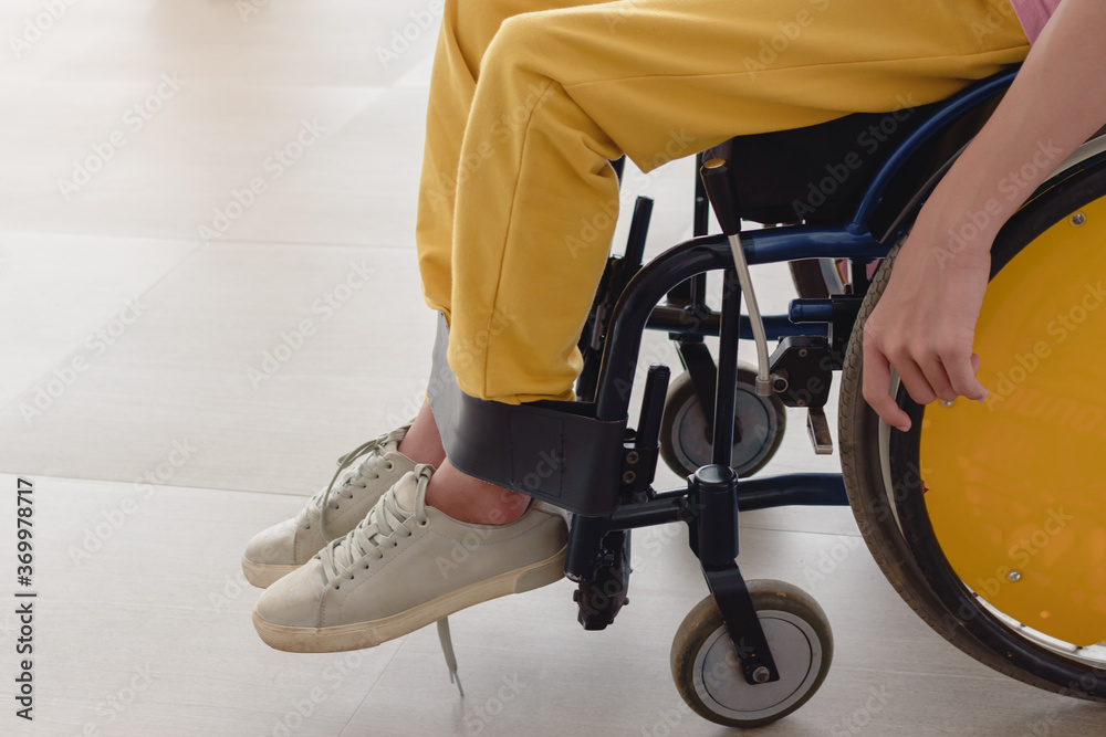 Obraz premium Close up photo of disable child sitting on the wheelchair in hospital walk way, His hand controlling the wheel, Life in the education age of children, Happy cerebral palsy kid concept.