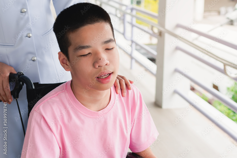 Asian special child on wheelchair is smile happily with nurse on ramp for disabled people background and orange light,Lifestyle in the education age of disabled children,Happy disability kid concept. Asian special child on wheelchair is smile happily with nurse on ramp for disabled people background and orange light,Lifestyle in the education age of disabled children,Happy disability kid concept.