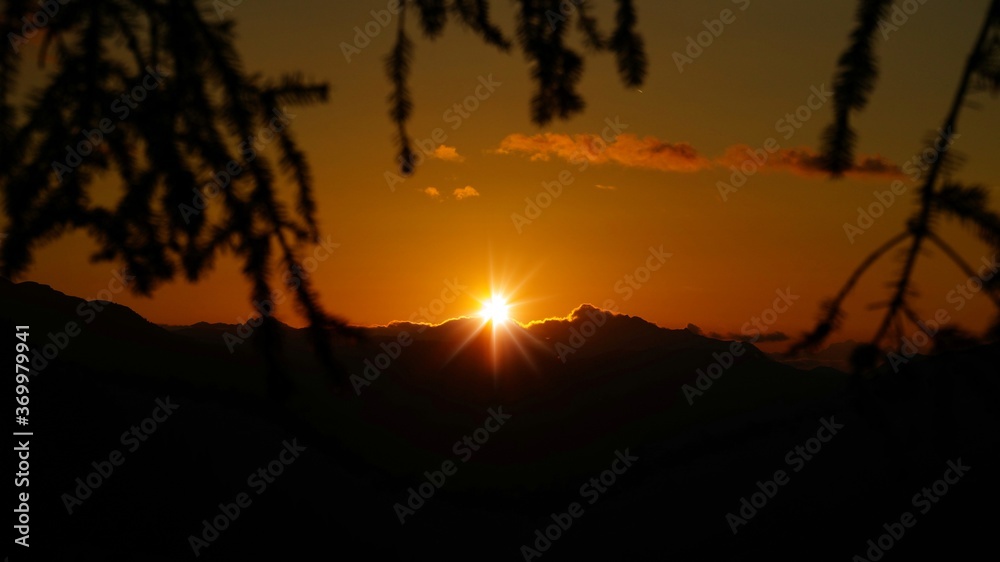 golden hour on the mountains with orange sky, mountain silhouette and view to the alps