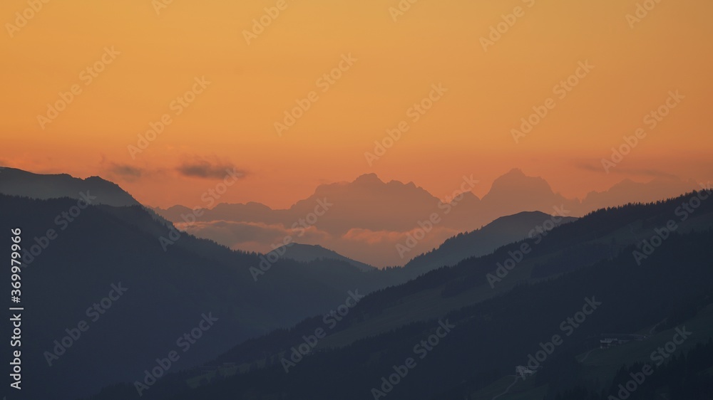 beautiful sunset on the mountains with orange sky and view to the alps
