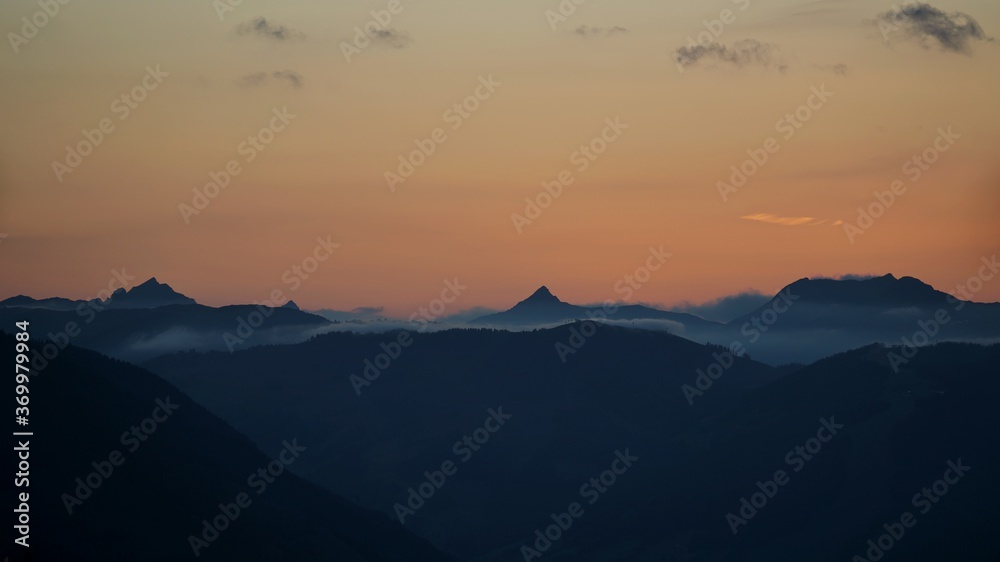 beautiful sunset on the mountains with orange sky and view to the alps