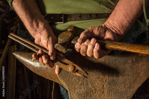 A farrier's hands clasped above an anvil photo