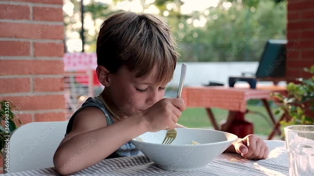 Child having dinner with a bowl of boiled potatoes with parsley at the sunset under the porch of the house after a hot summer day
Child having dinner with a bowl of boiled potatoes with parsley at the sunset under the porch of the house after a hot summer day