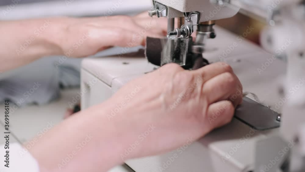 Old woman use sewing machine. Designes sew cloth. Brunette in studio. Old woman use sewing machine. Designes sew cloth. Brunette in studio.