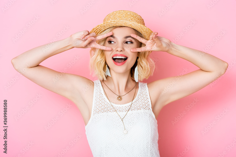 young woman in straw hat showing peace sign on pink young woman in straw hat showing peace sign on pink