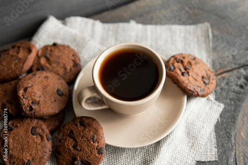 Coffee cup with cookies on wooden table background. Mug of black coffee with chocolate cookies. Fresh coffee beans.