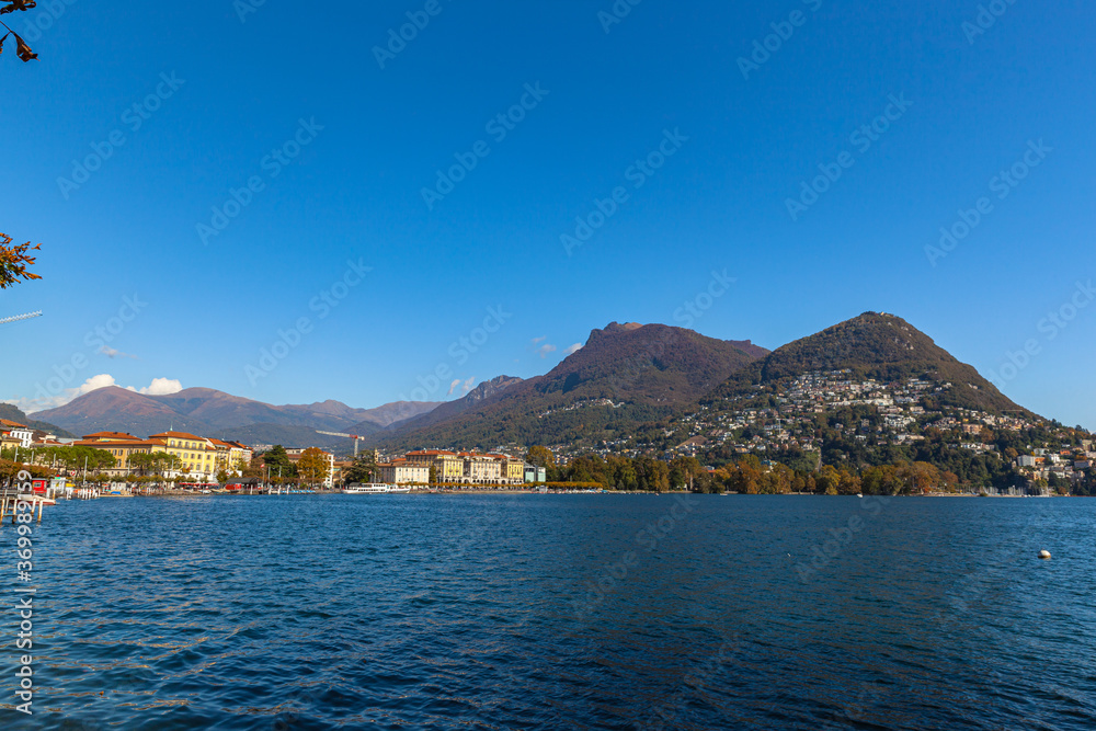 Stunning  panorama view of Lugano Lake, cityscape of Lugano, mountain Monte Bre and Swiss Alps on a sunny autumn day with blue sky cloud, cruise ship, Canton of Ticino, Switzerland
