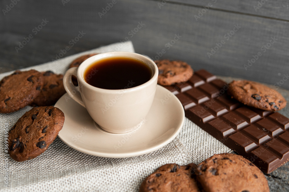 Coffee cup with cookies and chocolate on wooden table background. Mug of black coffee with chocolate cookies. Fresh coffee beans. Coffee cup with cookies and chocolate on wooden table background. Mug of black coffee with chocolate cookies. Fresh coffee beans.