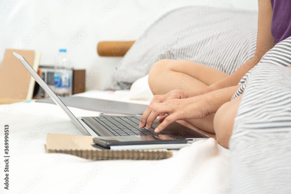 Fototapeta premium Womans sitting on bed in bedroom working with computer.