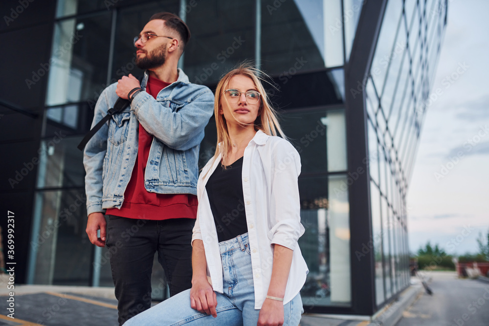 Young stylish man with woman in casual clothes outdoors together near business building. Conception of friendship or relationships Young stylish man with woman in casual clothes outdoors together near business building. Conception of friendship or relationships