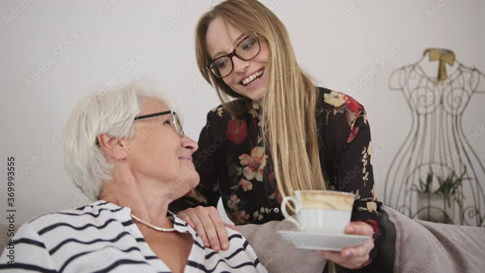 Young caucasian woman offering a tea to an elderly lady. Slow motion. High quality 4k footage Young caucasian woman offering a tea to an elderly lady. Slow motion. High quality 4k footage
