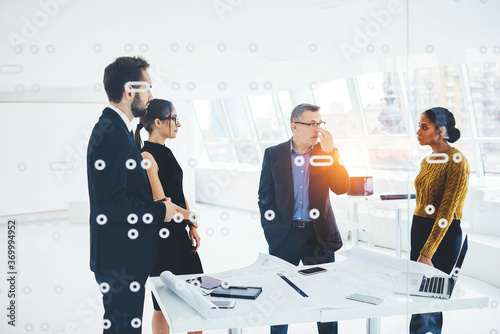 Experienced mature male owner of business corporation supervising work of staff members motivate them on meeting, partners communicating during parleys discussing contract details on conference photo