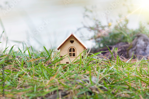 A wooden house with a heart and sun rays, stands on the green grass on the lake shore . The concept of selling, buying, renting real estate, family home, home for children, insurance, Happy life in yo