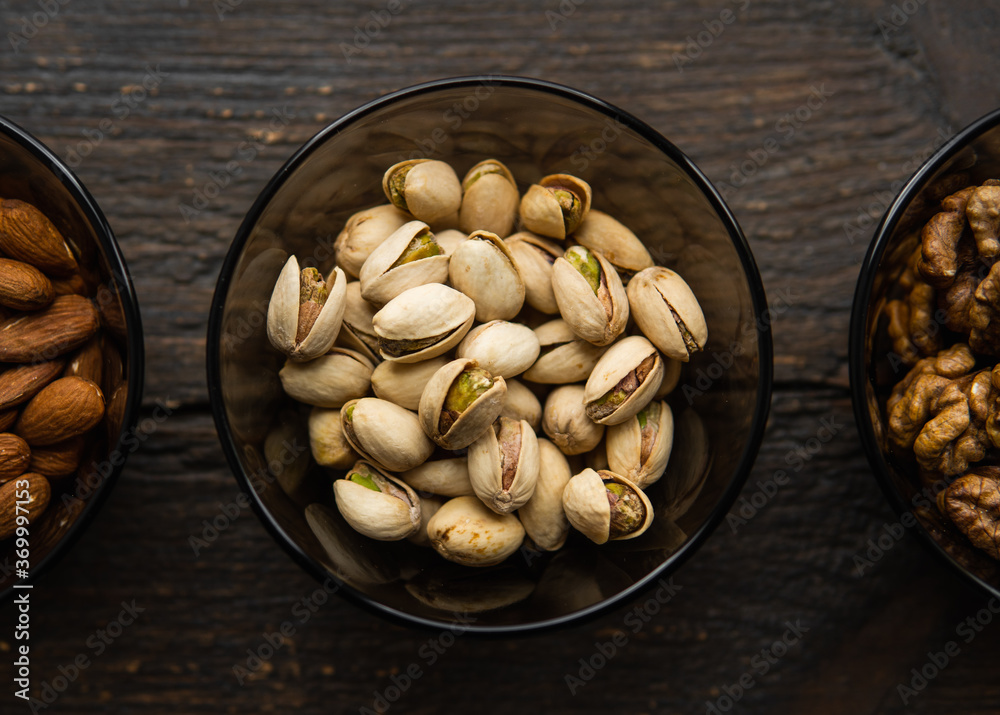 Almond, pistachio and walnut in a small plates which standing on a black table. Nuts is a healthy vegetarian protein and nutritious food. Almond, pistachio and walnut in a small plates which standing on a black table. Nuts is a healthy vegetarian protein and nutritious food.