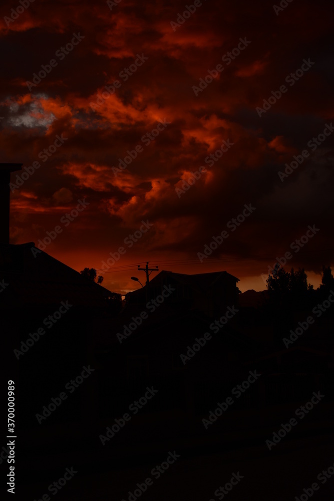 Fototapeta premium The sun is setting in a burnt orange sky as the city transforms into beautiful black silhouettes