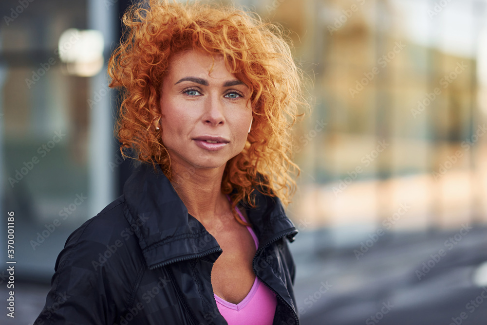 Young european redhead woman in sportive clothes standing outdoors Young european redhead woman in sportive clothes standing outdoors