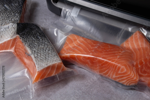 Piece of gourmet oceanic salmon vacuum packed in clear plastic ready for freezing lying on a wooden table. Top View