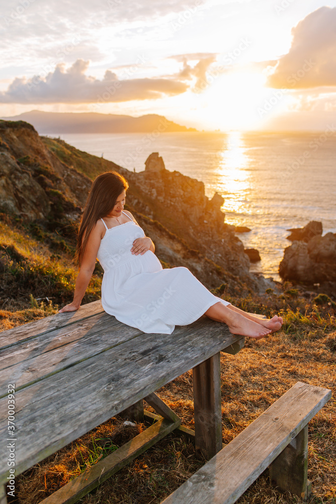 Pregnant woman against an oceanic landscape at sunset