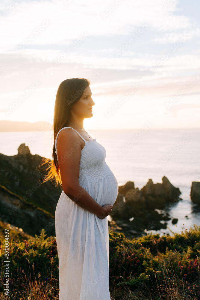 Side view of a pregnant woman against an oceanic landscape