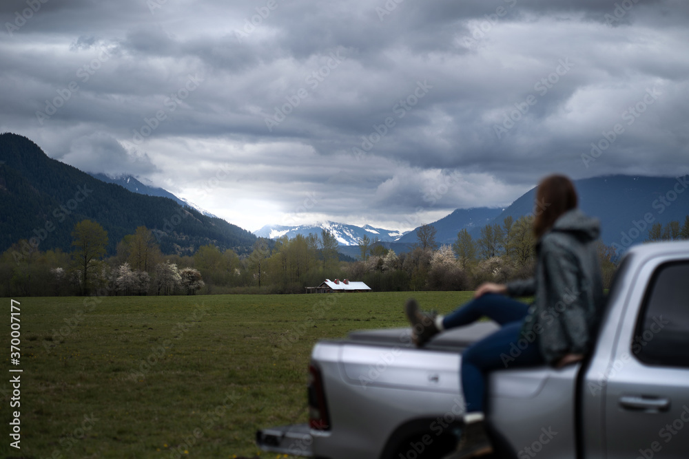 Woman sitting on truck watching sky and mountains