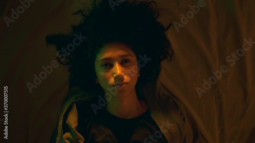Close-up of a black haired girl with a deep gaze who is lying on the bed. Dolly shot