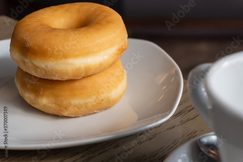 Two fresh donuts for breakfast on a wooden table  espresso cup