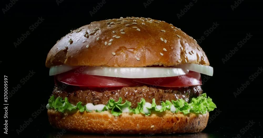Yummy juicy burger with fresh ingredients rotating in front of camera. Delicious hamburger with grilled beef steak served on chef's table 4k footage close up shot