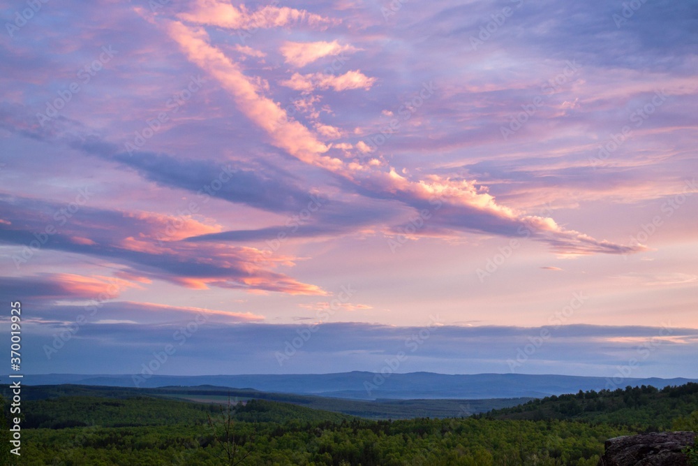 Obraz premium sunset on the forest hills, clouds in shape of airplane
