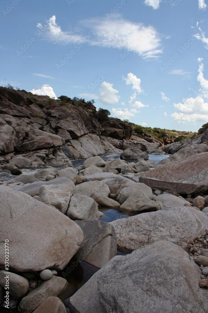 Vertical photo. View of the rocks and river flowing downhill in the stone valley. Vertical photo. View of the rocks and river flowing downhill in the stone valley.