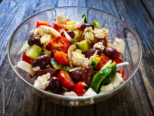 Fresh Greek salad - feta cheese, cherry tomatoes, lettuce, black olives and onion on wooden table