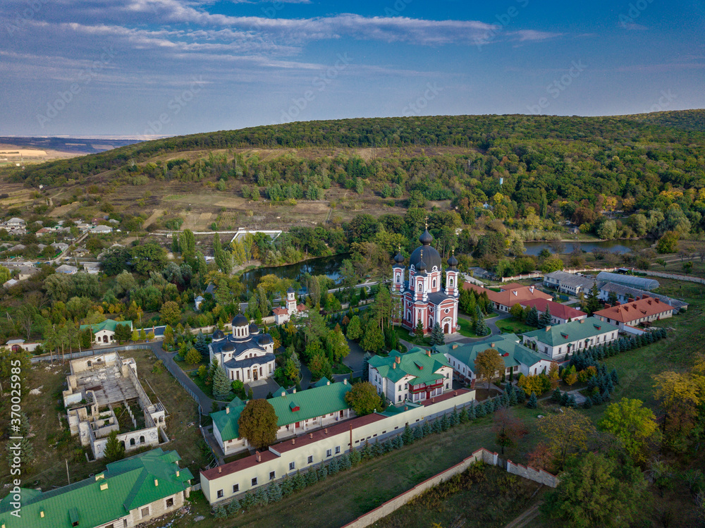 Flight over a christian monastery surrounded by autumn forest. Kurky monastery, Moldova republic of.