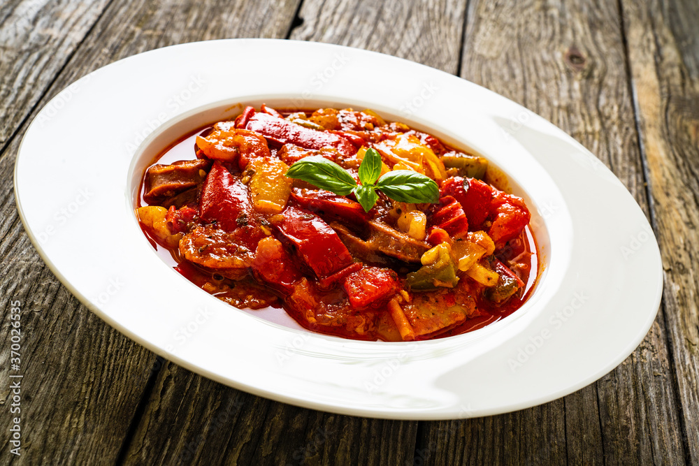 Delicious stew - vegetable with sausages on wooden table Delicious stew - vegetable with sausages on wooden table