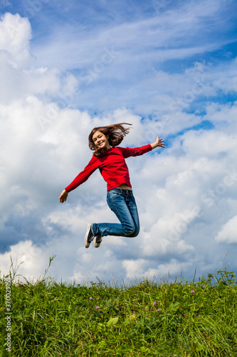 Girl jumping, running against cloudy sky 