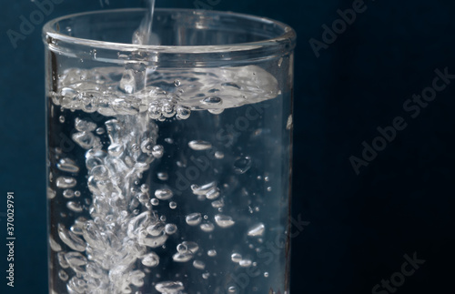 Pouring water into a glass on a dark blue background
