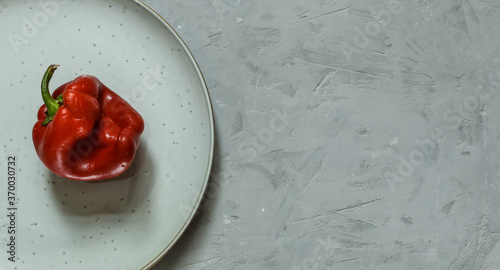  ugly red pepper on a plate, against a rough gray background. Horizontal orientation with space, top photo