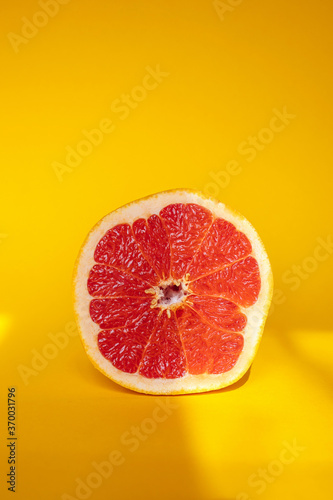 Half of grapefruit on orange background with sun stripes photo