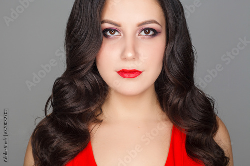 Portrait of a beautiful woman, a brunette model with makeup on a gray background. Concept photo for the magazine.